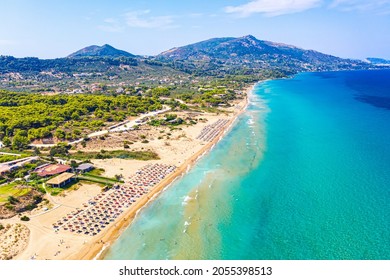 Top view aerial drone photo of Banana beach with beautiful turquoise water, sea waves and red umbrellas. Vacation travel background. Ionian sea, Zakynthos Island, Greece.