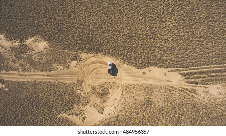 Top view aerial photo from drone of a riding pickup machine in sandy steppe during amazing trip to Asia. Professional rider is drifting in desert arid wilderness leaving circle trails of the tires
