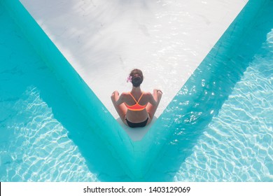 Top view aerial photo of model in bright swimwear relaxing in hotel pool during her summer weekend