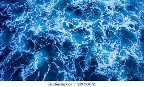 Top View Aerial Photography White Sea Foam Against The Background Of The Blue Sea Or Ocean. Background, Screensaver