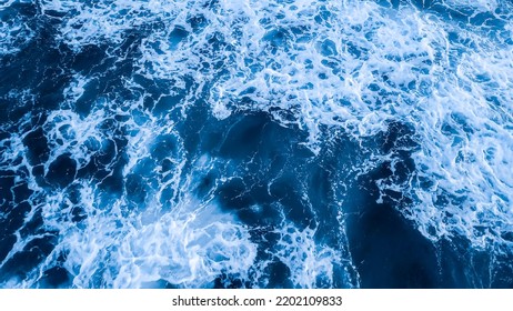 Top view aerial photography white sea foam against the background of the blue sea or ocean. Background, screensaver