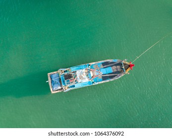 Top view, aerial view wooden fishing boat on the beach from a drone. Royalty high quality stock photo image of the wooden fishing boat on the beach. Fishing boat is mooring on clear bluw beach alone
