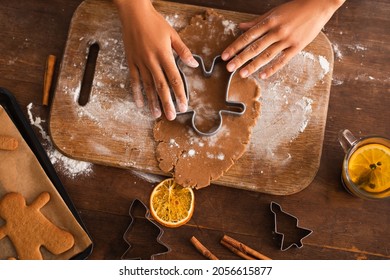 Top view of african american woman pressing christmas cookie cutter on dough near cinnamon sticks in kitchen