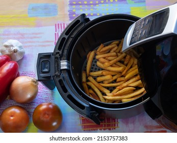 Top View Of An Air Fryer On A Table With French Fries And Vegetables. Healthy Food Concept.