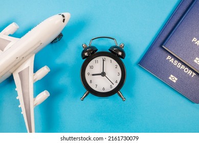 Top View Alarm Clock With Toy Airplane, Passports On Blue. Flight Time. The Concept Of Tourism And Travel.