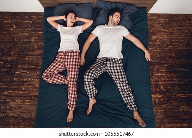 Top View. Alarmed Young Woman Closes Ears Because Of Loud Snoring Of Adult Man Sleeping Nearby. Family Snoring Concept. Problem Of Loud Snoring.