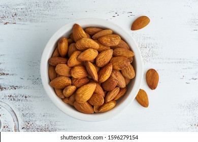 Top View Almonds Nuts In A White Bowl On A White Wooden Cutting Board. Wooden Background, Overhead, Close Up