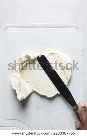 Top view of american buttercream being spread out with a small spatula, buttercream with air pockets, textured buttercream