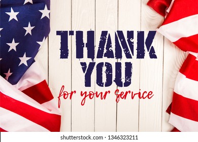 top view of american flags and thank you for your service lettering on white wooden surface