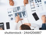 Top view analyst team utilizing BI Fintech to analyze financial data at table in meeting room. Analytic BI dashboard power on paper for business insight and strategic marketing planning. Prudent