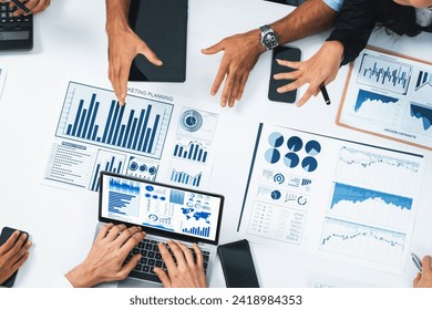 Top view analyst team utilizing BI Fintech to analyze financial data at table in meeting room. Analytic BI dashboard power on paper for business insight and strategic marketing planning. Prudent