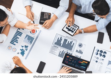 Top view analyst team utilizing BI Fintech to analyze financial data at table in meeting room. Analytic BI dashboard power on paper for business insight and strategic marketing planning. Prudent