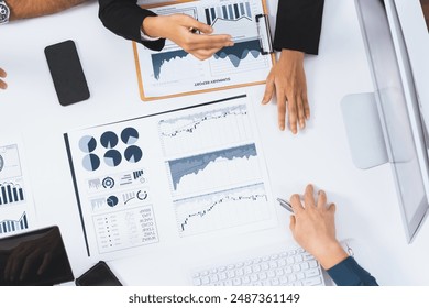 Top view analyst team utilizing BI Fintech to analyze financial data at table in meeting room. Analytic BI dashboard power on paper for business insight and strategic marketing planning. Prudent