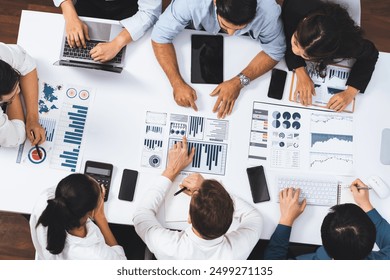 Top view analyst team utilizing BI Fintech to analyze financial data at table in meeting room. Analytic BI dashboard power on paper for business insight and strategic marketing planning. Prudent