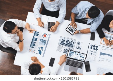 Top view analyst team utilizing BI Fintech to analyze financial data at table in meeting room. Analytic BI dashboard power on paper for business insight and strategic marketing planning. Prudent