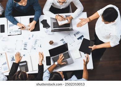 Top view analyst team utilizing BI Fintech to analyze financial data at table in meeting room. Analytic BI dashboard power on paper for business insight and strategic marketing planning. Prudent