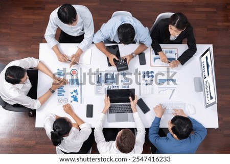 Top view analyst team utilizing BI Fintech to analyze financial data at table in meeting room. Analytic BI dashboard power on paper for business insight and strategic marketing planning. Prudent