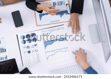 Top view analyst team utilizing BI Fintech to analyze financial data at table in meeting room. Analytic BI dashboard power on paper for business insight and strategic marketing planning. Prudent