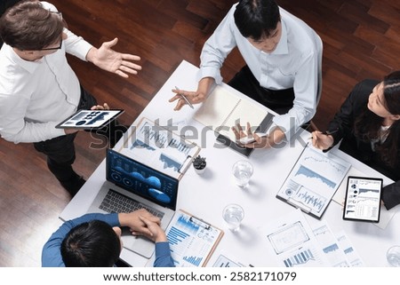 Top view analyst team utilizing BI Fintech to analyze financial data at table in meeting room. Analytic BI dashboard power on paper for business insight and strategic marketing planning. Prudent