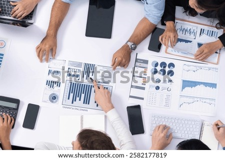 Top view analyst team utilizing BI Fintech to analyze financial data at table in meeting room. Analytic BI dashboard power on paper for business insight and strategic marketing planning. Prudent