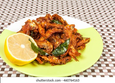 Top View Of Anchovies Fish Fry In A Plate  With Lemon. This Fish Is Also Know As Netholi, Nethili & Kozhuva In South India Which Is Spicy Seafood.