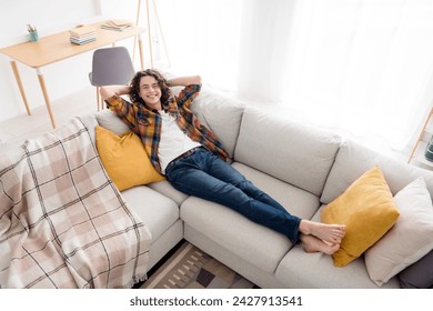 Top view angle photo of dreamy funky guy wear plaid shirt lying sofa arms behind head indoors room home house - Powered by Shutterstock