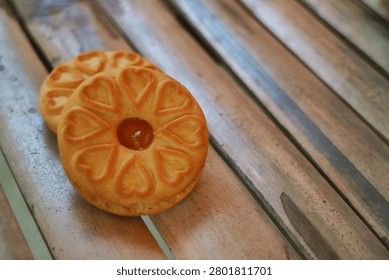 Top view angle of two sweet cookies with fruit jam filling on a bamboo slatted table. Heart shaped pattern cookies with pineapple jam filling placed on a rustic bamboo table.