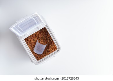 Top View Of Animal Feed, Ready To Eat Pellets Food Multi Nutrients For Cat And Dogs Or Pet, Dried Storage Or Container Plastic Box With Measuring Cup On White Background With Copy Space.