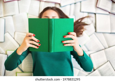 
Top View Of Anonymous Female Student Lying On Books And Reading During Exam Preparation