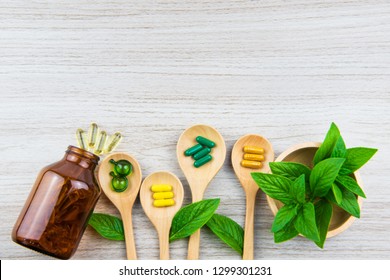 Top view of antioxidants vitamin, pills, drug, capsule in wooden spoon, organic herbal medicine from nature green leaf supplemental and health care product on medical wooden background with copy space - Powered by Shutterstock