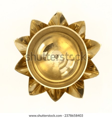 top view of an antique oil wick lamp in lotus flower shape made of golden brass used for aarti worship in temple ceremony isolated in a white background