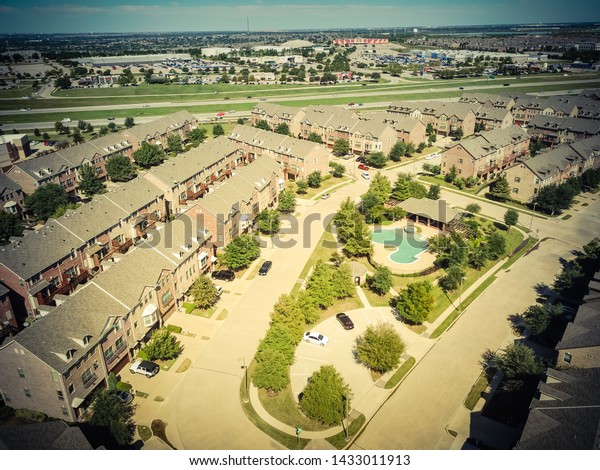 Top view apartment complex near\
highway 635 and strip mall, marketplace suburban Dallas, Texas.\
Multistory rental building with swimming pool and attached\
garages