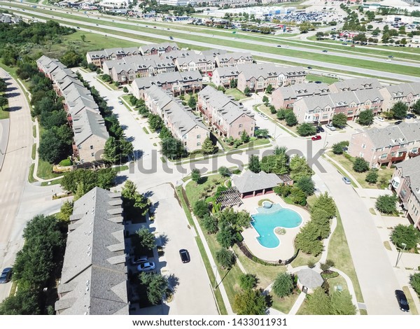 Top view apartment complex near\
highway 635 and strip mall, marketplace suburban Dallas, Texas.\
Multistory rental building with swimming pool and attached\
garages