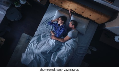 Top View Apartment: Happy Young Couple Side Cuddling Together in the Bed Sleeping at Night. Beautiful Girlfriend and Handsome Boyfriend Sleeping Together. Family of two Sweetly Embracing Each other - Powered by Shutterstock