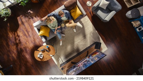 Top View Apartment: Lovely Couple Watching Television in the Stylish Living Room. Looking at the TV Display and Eating Popcorn. Girlfriend and Boyfriend Enjoy Sitcom on Streaming Service on Couch. - Powered by Shutterstock