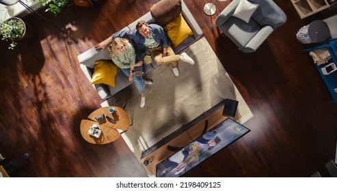 Top View Apartment: Lovely Happy Couple Watching Television in the Stylish Living Room. Looking Up at the Camera and Smile. Girlfriend and Boyfriend Enjoy Sitcom on Streaming Service Sitting on Couch - Powered by Shutterstock