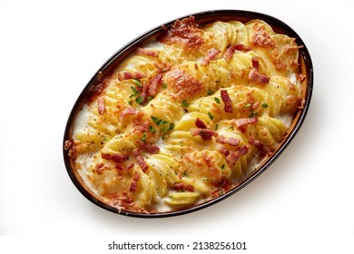 Top view of appetizing gratin with baked sliced potato and crispy bacon pieces baked in oval shaped pan placed on white background