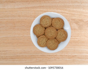 Top View Of Apple Pie Crust Cookies On A White Plate Atop A Wood Table.