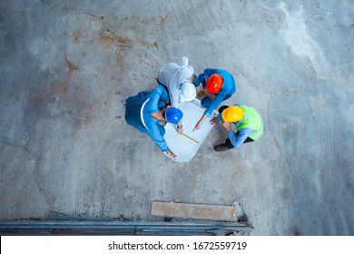 Top view of architects and engineer working on his blueprints with documents on construction site. meeting, discussing, designing, planing, serious civil engineer working 