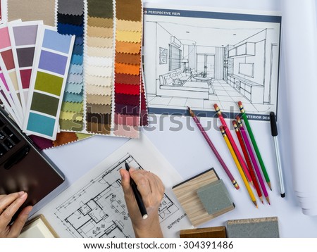 Top view of architects hands drawing of modern house with material sample on creative desk