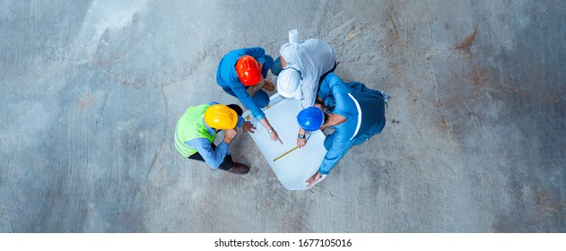 Top view of architectural engineer working on his blueprints with documents on construction site. meeting, discussing,designing, planing - Powered by Shutterstock