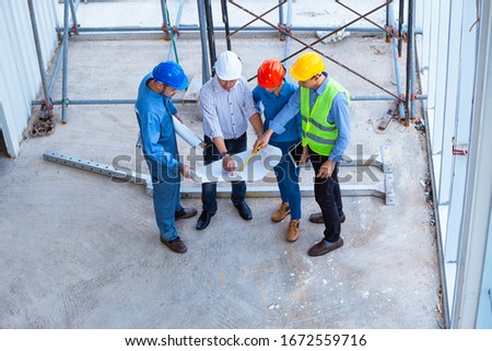 Top view of architectural engineer working on his blueprints with documents on construction site. meeting, discussing,designing, planing, serious civil engineer working 