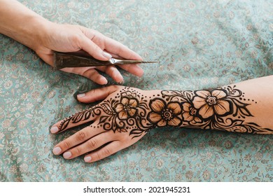 Top View Art Henna Tattoo On Woman Hands. Master Artist Drawing Arabic Mehndi For Bride Before Wedding. Close-up, Overhead View. Floral Design. Cone