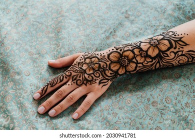 Top view art henna tattoo on woman hands. master artist drawing Arabic mehndi for bride before wedding. Close-up, overhead view. Floral design. Cone