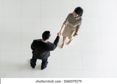 Top View Of Asian Businessman And Businesswoman Shaking Hands In Office Lobby. Welcome To Business.
