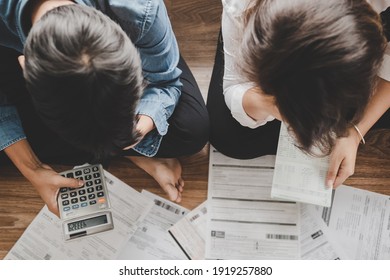 Top view asian couple sitting on the floor stressed and confused by calculate expense from invoice or bill,have no money to pay think of taking the house to mortgage causing debt,bankruptcy concept.