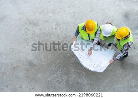 Top view of Asian engineer or Young Female Architect put on a helmet for safety and talk with a contractor on a construction building factory project, Concept of Teamwork, Leadership concept.