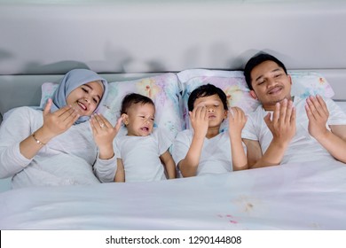 Top View Of Asian Family Praying Before Sleep While Lying Together On The Bed