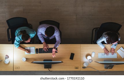 Top View Of Asian Male Customer Care Service Working Hard Late In Night Shift At Office,call Center Department,worker And Overtime,team Work With Colleagues For Success Concept