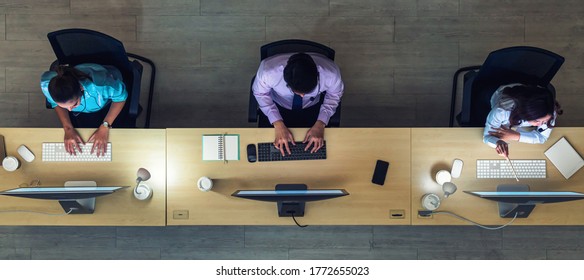 Top View Of Asian Male Customer Care Service Working Hard Late In Night Shift At Office,call Center Department,worker And Overtime,team Work With Colleagues For Success Concept